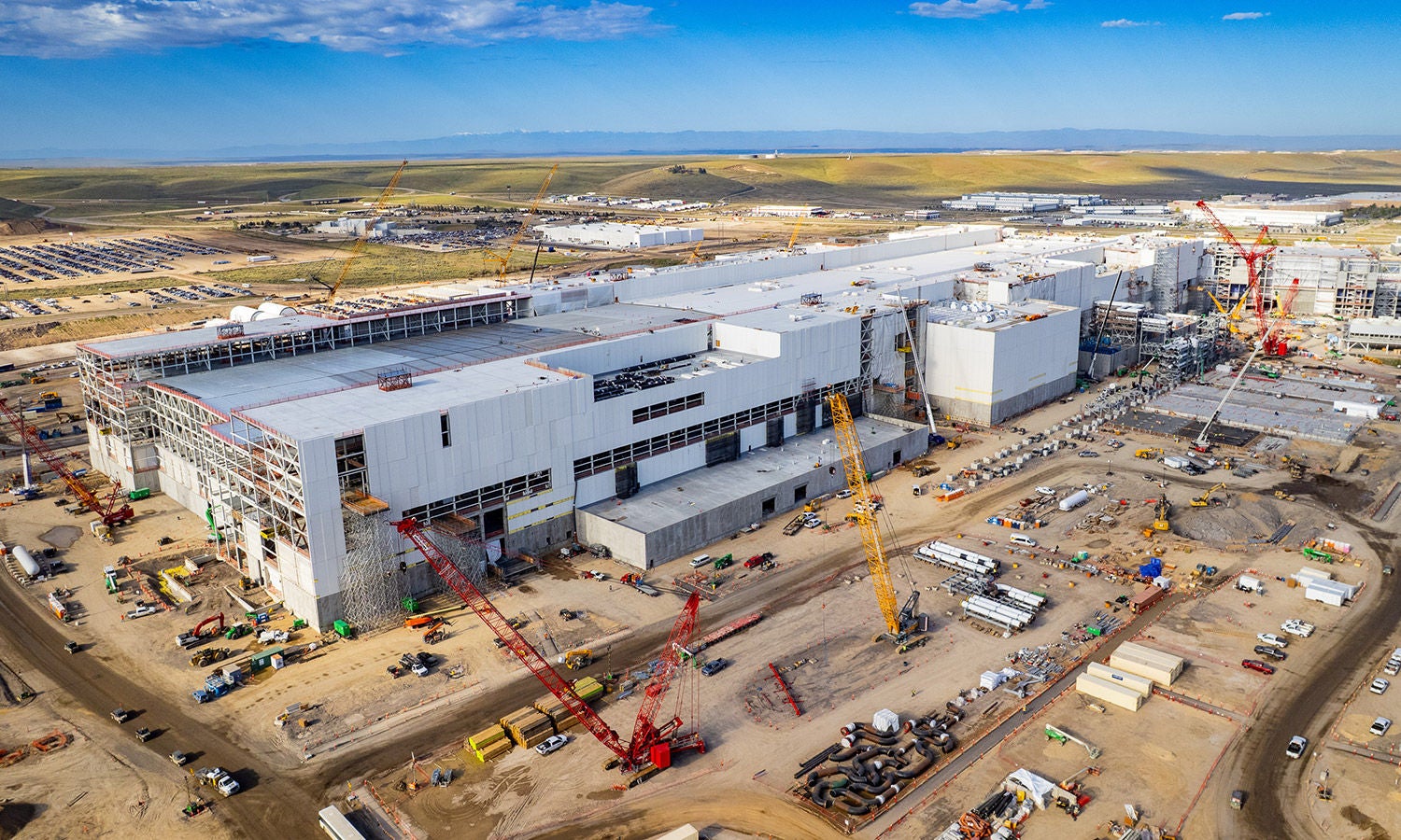 Aerial view of Micron's Boise fab megastructure under construction, cranes rising over the Idaho plain